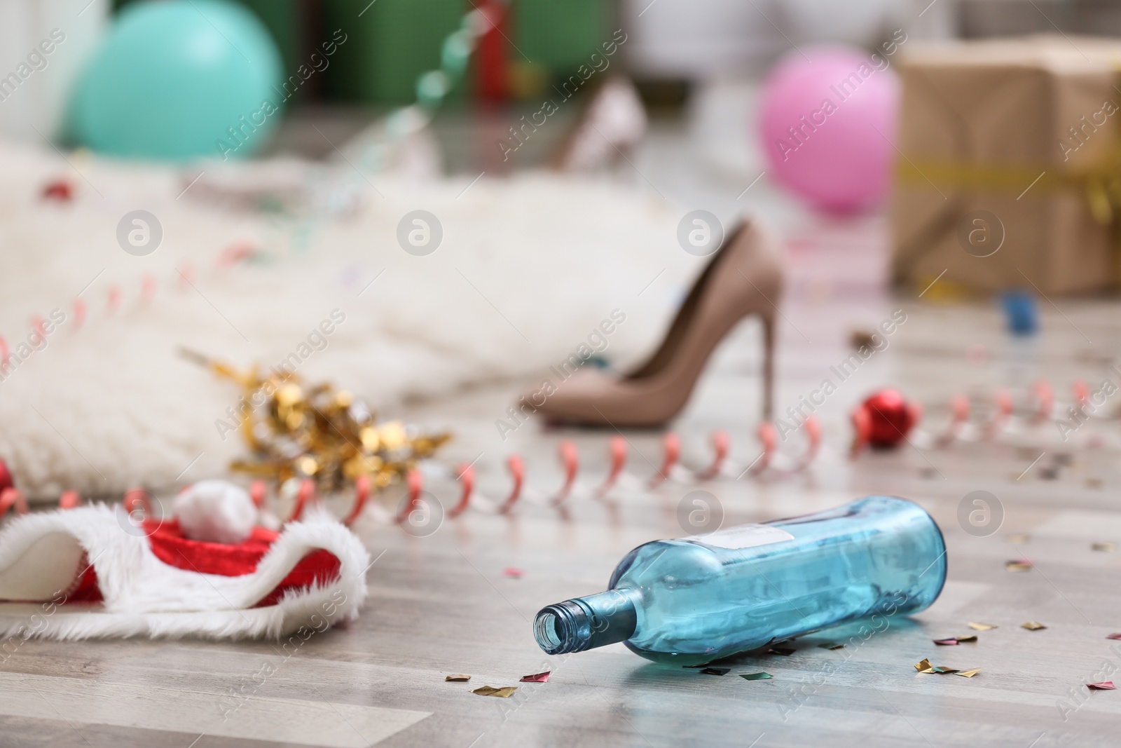 Photo of Empty bottle and Santa hat on messy floor. Chaos after party