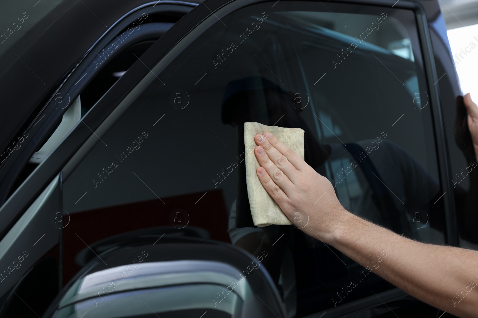 Photo of Worker tinting car window with foil in workshop, closeup