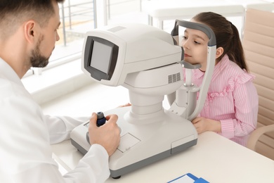 Photo of Ophthalmologist examining little girl in clinic