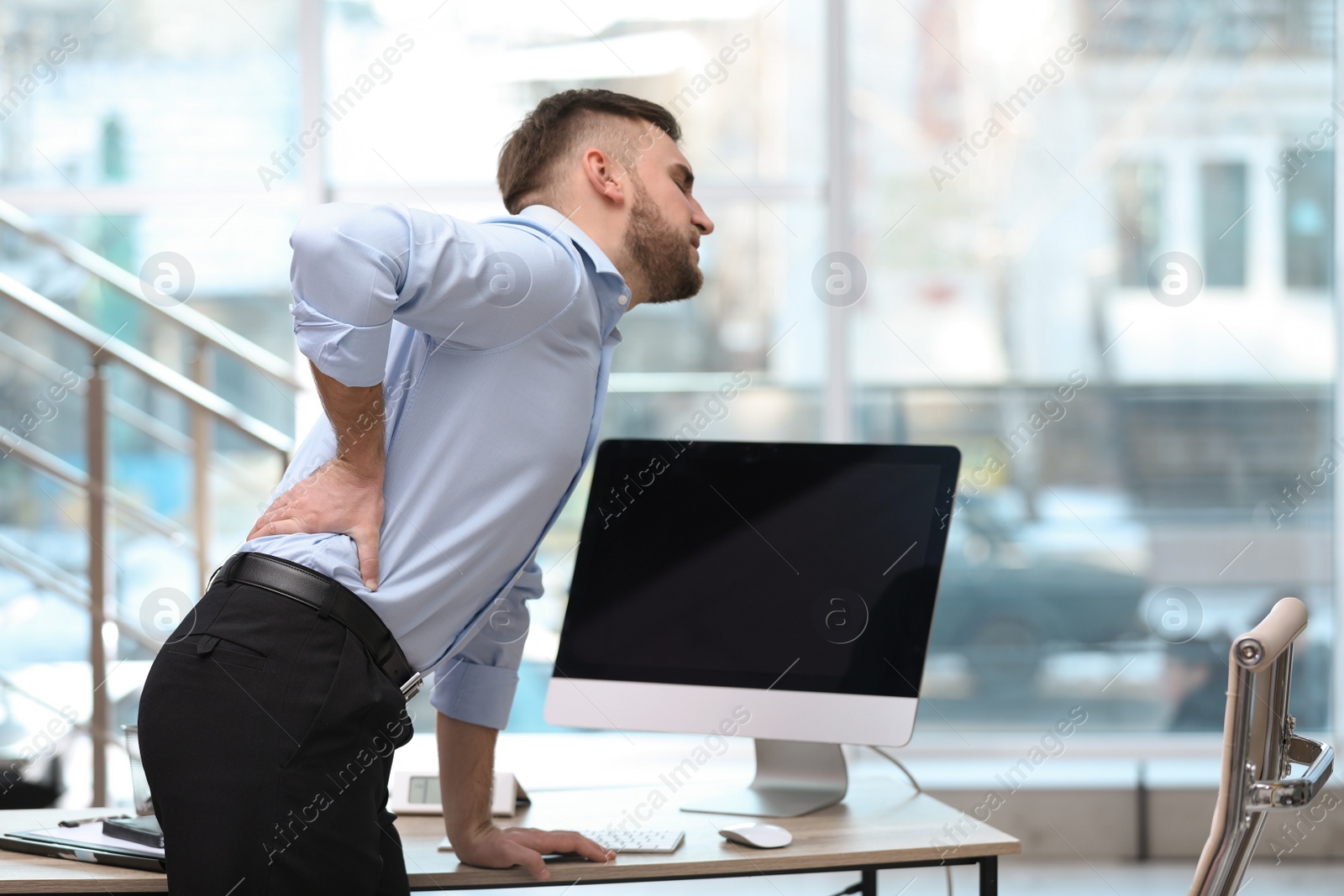 Photo of Businessman suffering from back pain at workplace