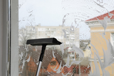 Cleaning window with squeegee indoors. Space for text