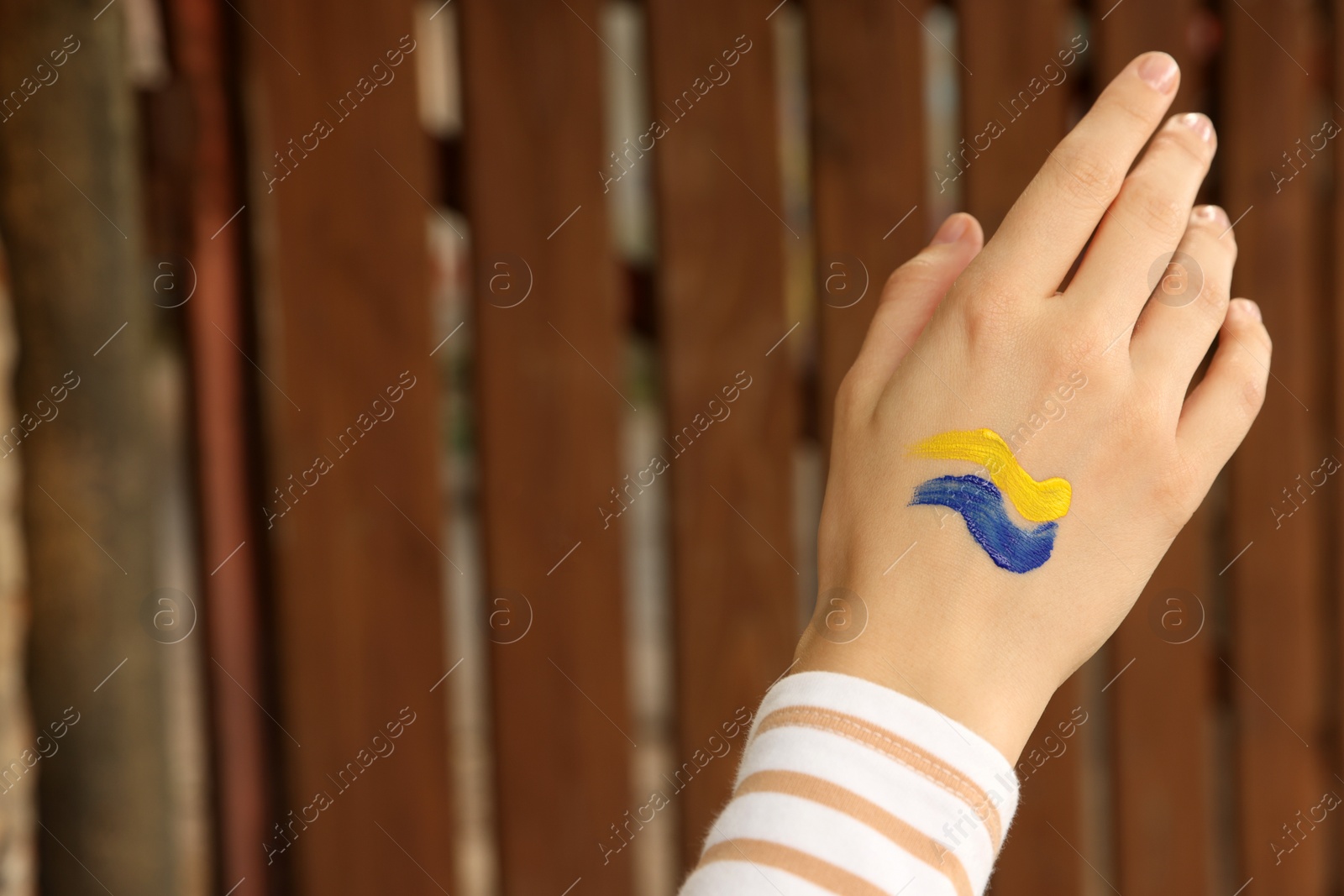 Photo of Woman with drawing of Ukrainian flag on hand outdoors, closeup. Space for text