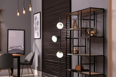 Photo of Stylish shelving unit with decor near grey wall indoors. Interior design