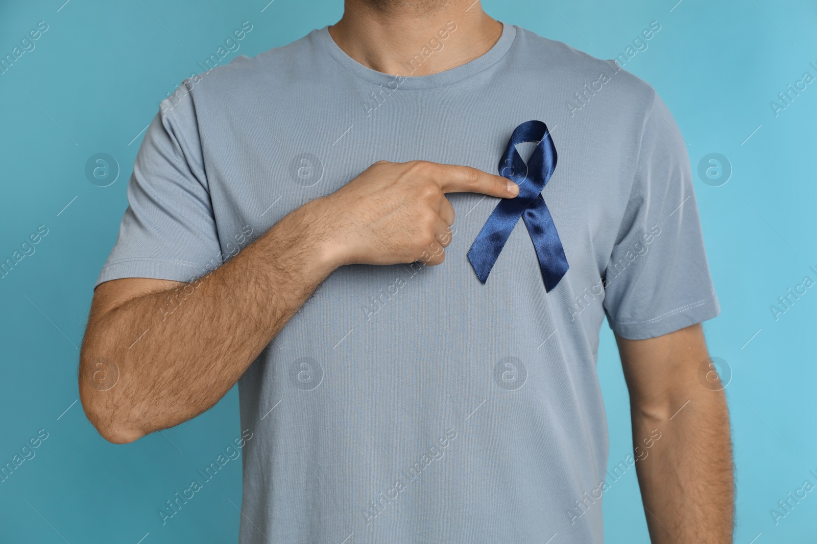 Photo of Man with ribbon on light blue background, closeup. Urology cancer awareness