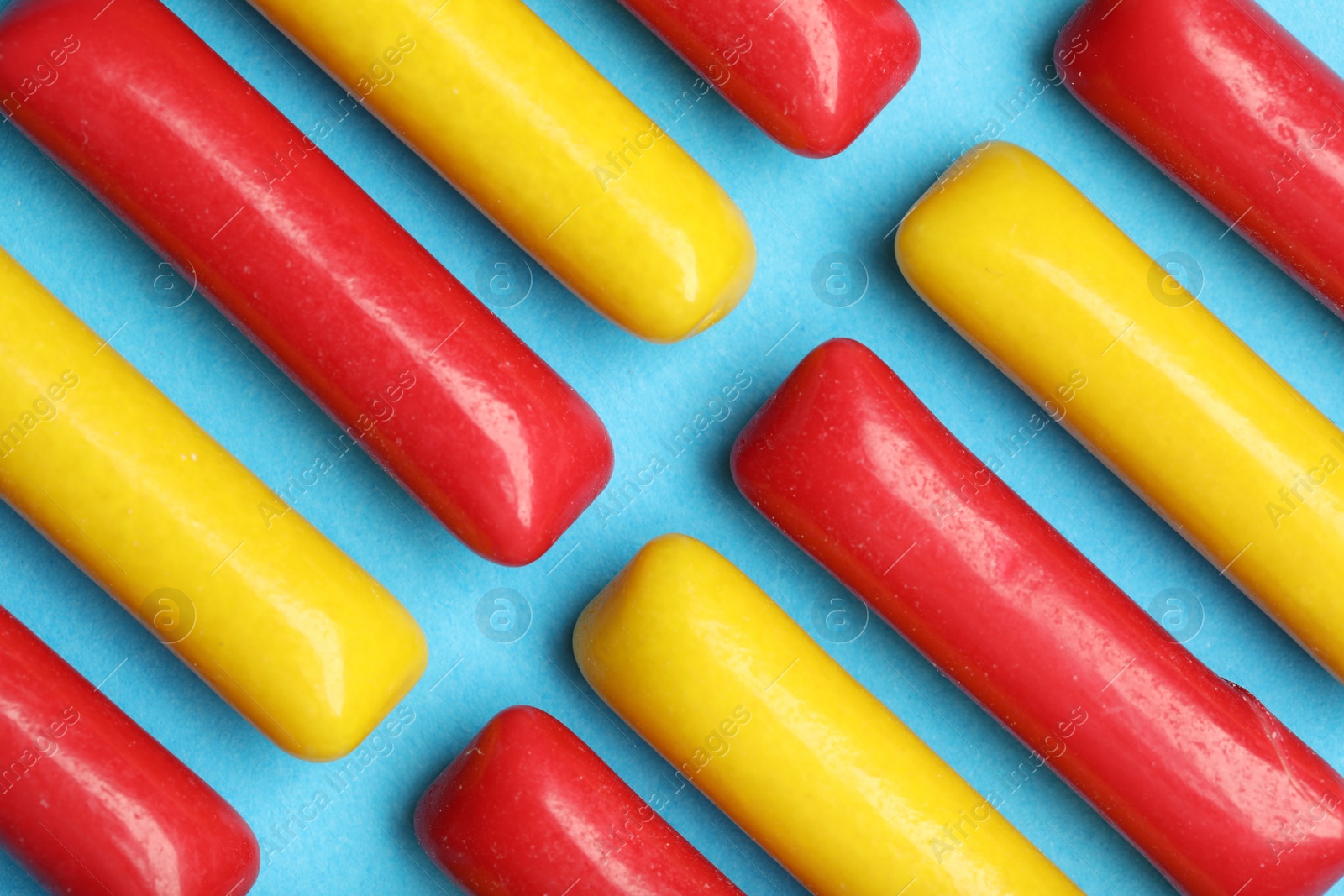 Photo of Many tasty bubble gums on light blue background, flat lay