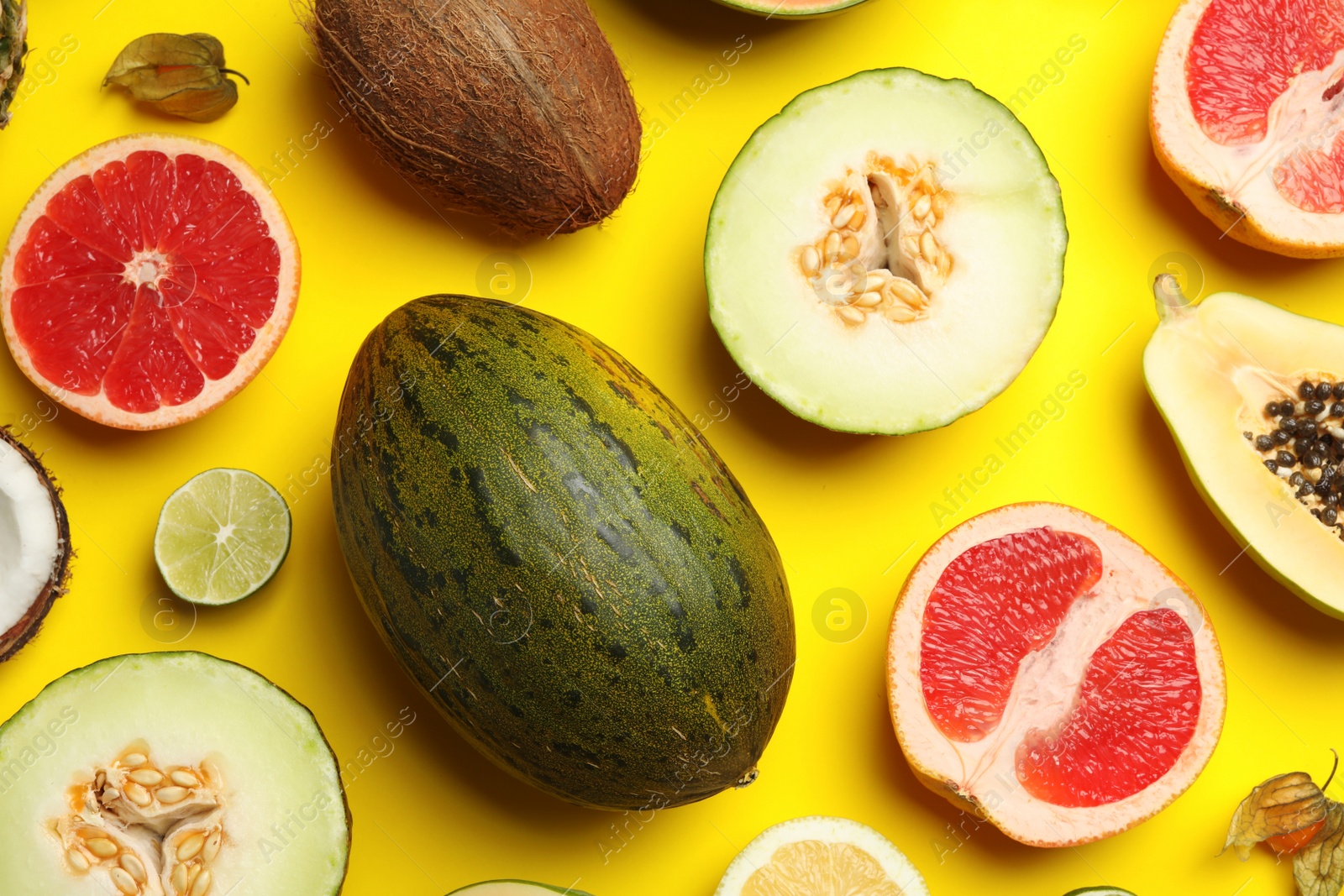 Photo of Flat lay composition with tasty melon and fresh tropical fruits on yellow background