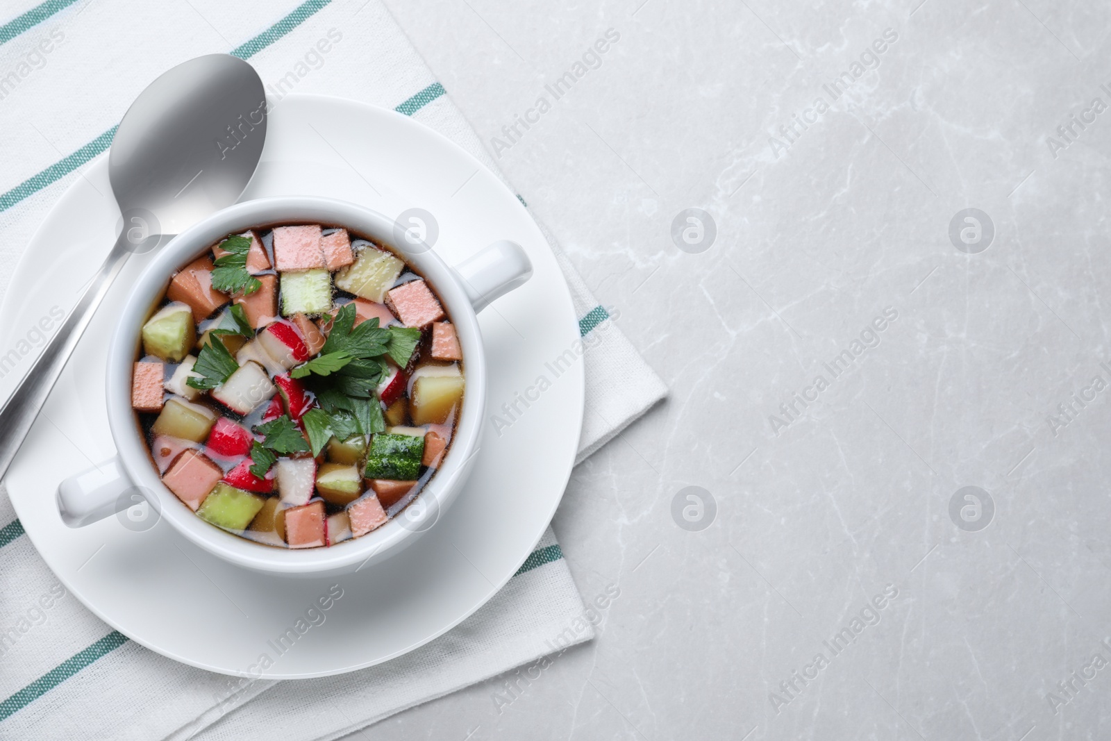 Photo of Delicious cold okroshka with kvass served on light grey table, top view and space for text. Traditional Russian summer soup