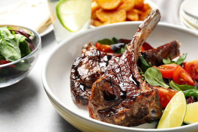 Photo of Delicious grilled ribs served on light grey table, closeup