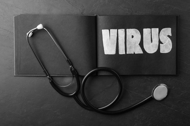 Photo of Notepad with word VIRUS and stethoscope on black background, flat lay