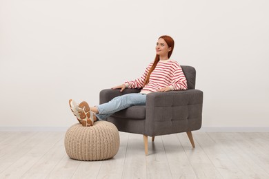 Photo of Beautiful young woman relaxing in armchair near white wall indoors