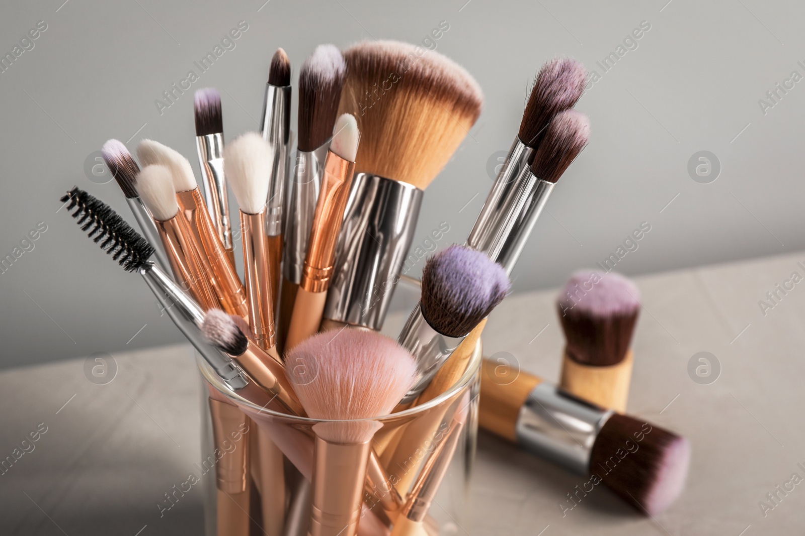 Photo of Set of professional makeup brushes on grey table, closeup