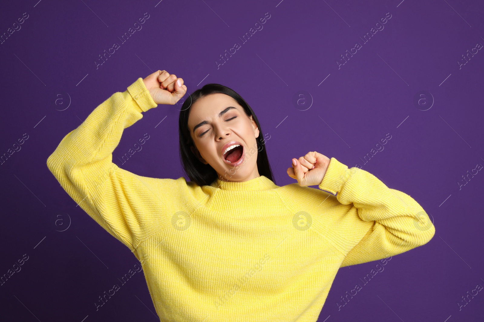 Photo of Young tired woman yawning on purple background