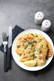 Delicious chicken piccata with herbs served on grey table, flat lay