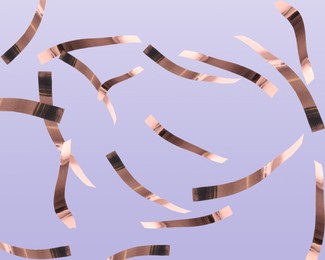 Image of Shiny bronze confetti falling on pale violet background