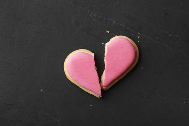 Photo of Broken heart shaped cookie on black table, top view with space for text. Relationship problems concept