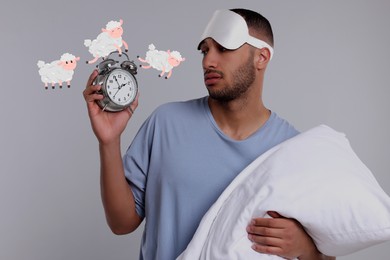 Image of Insomnia. Tired man with pillow checking time on light grey background. Illustrations of sheep jumping over alarm clock