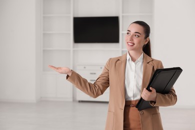 Photo of Happy real estate agent with leather portfolio showing new apartment