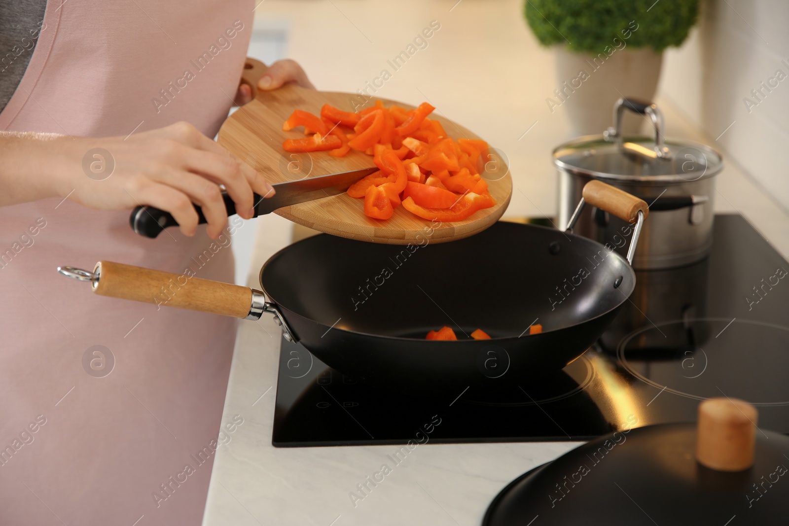 Photo of Young woman cooking on stove in kitchen, closeup