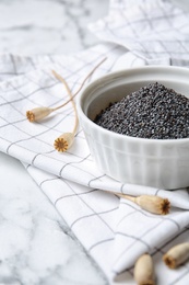 Photo of Dry poppy heads and bowl with seeds on table