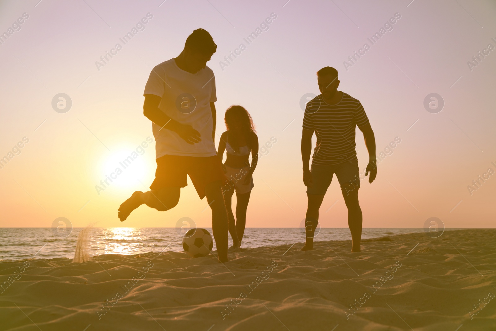 Photo of Friends playing football on beach at sunset