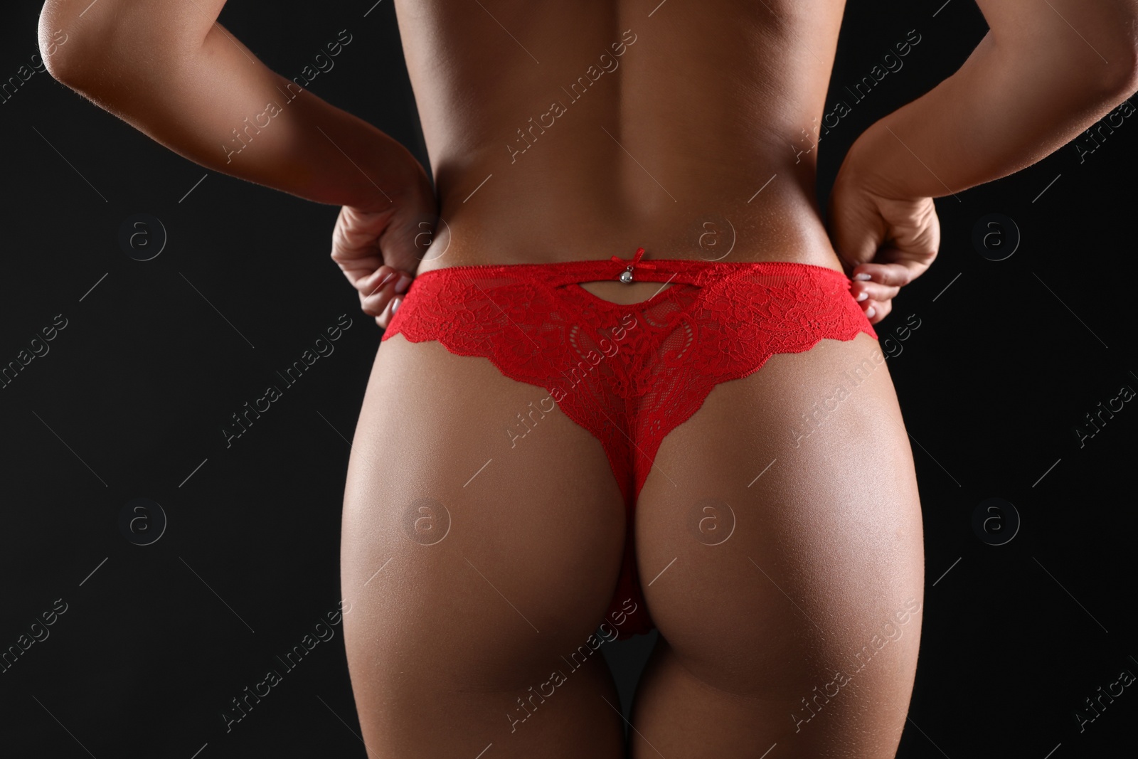 Photo of Woman in red sexy panties on black background, closeup