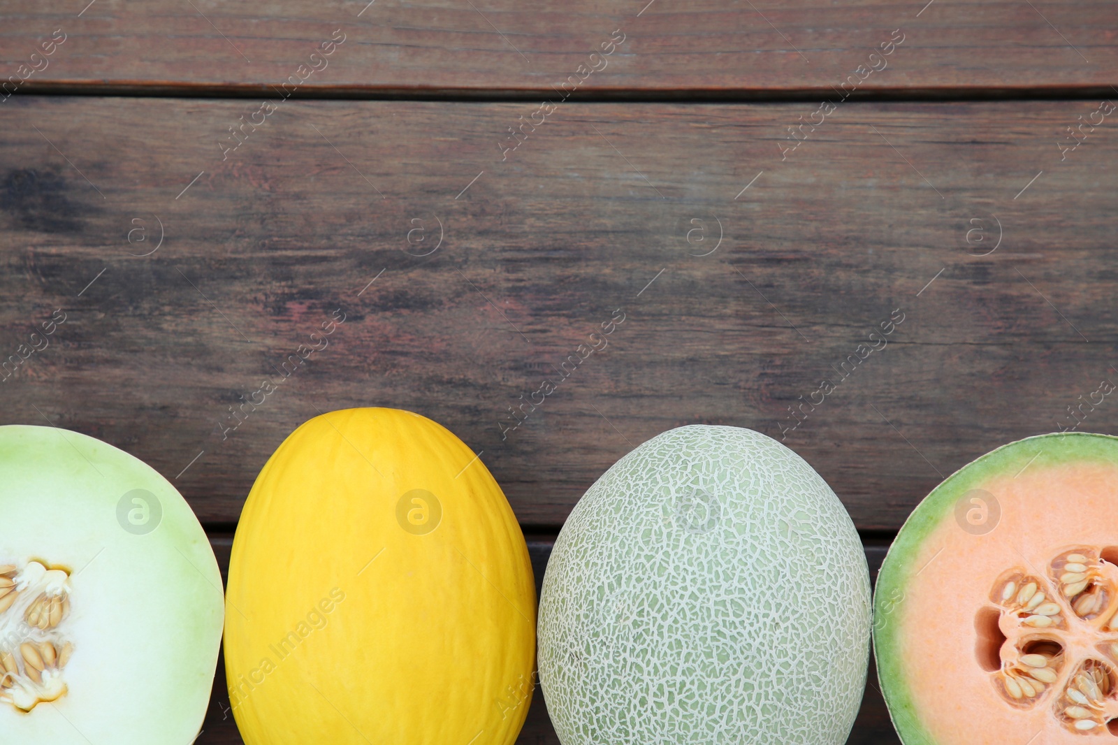 Photo of Different types of tasty ripe melons on wooden table, flat lay. Space for text