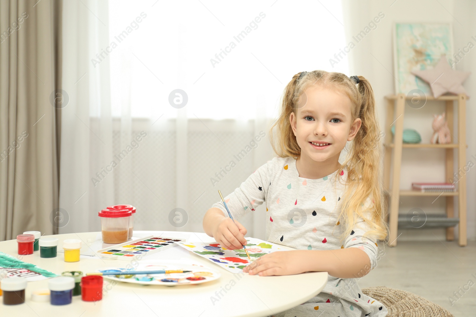 Photo of Cute little child painting at table in room