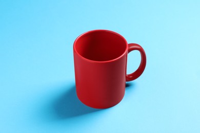 Photo of One red ceramic mug on light blue background