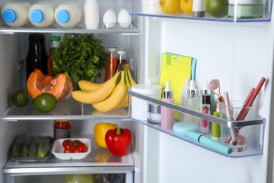 Photo of Storage of cosmetics and tools in refrigerator door bin next to groceries