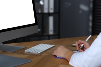 Photo of Doctor working with computer at table in office. Hotline service