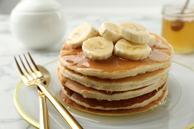 Photo of Delicious pancakes with bananas and honey on white table, closeup