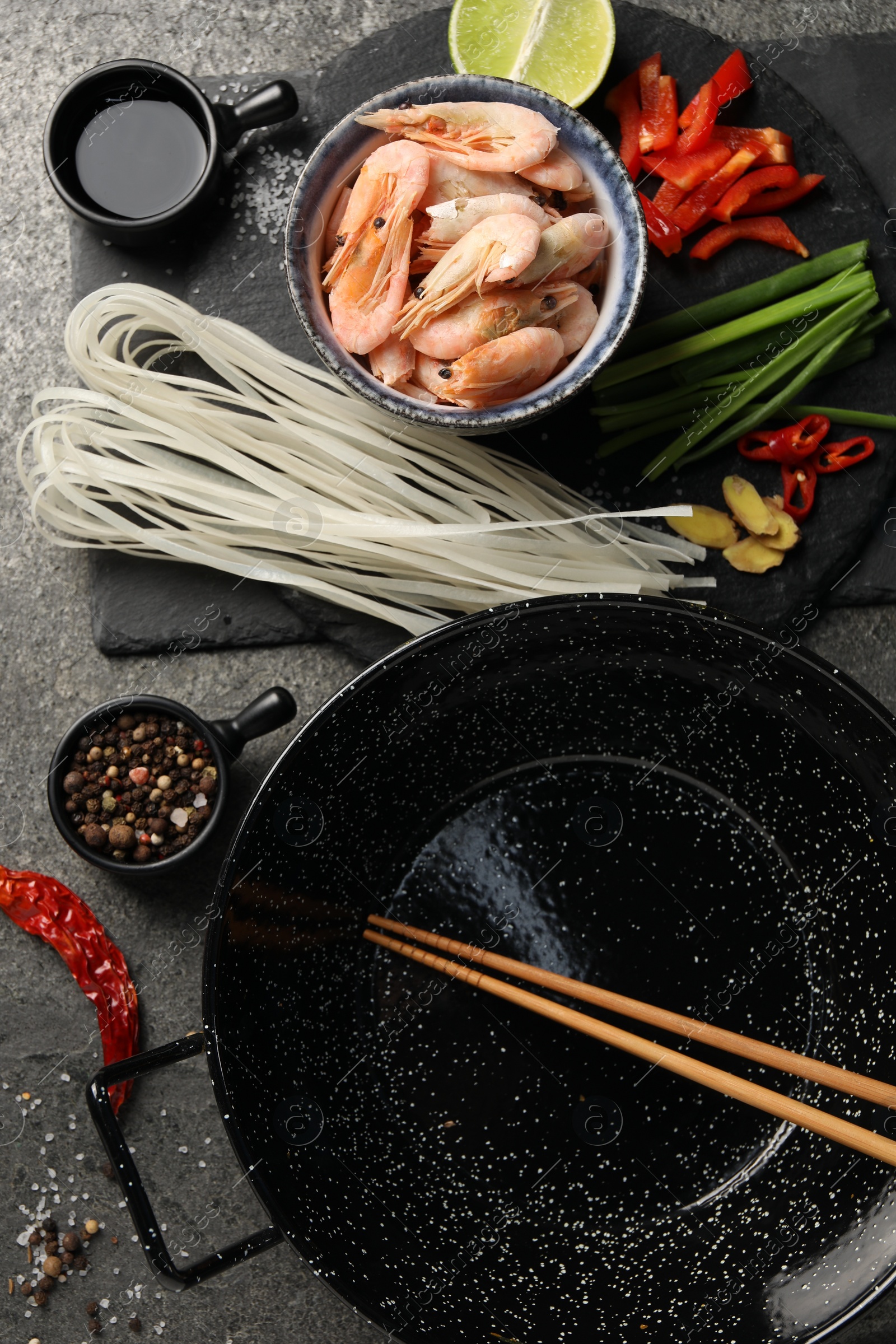 Photo of Flat lay composition with black wok, spices and products on dark textured table