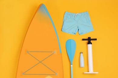 Photo of Flat lay composition with SUP board on orange background. Water sport