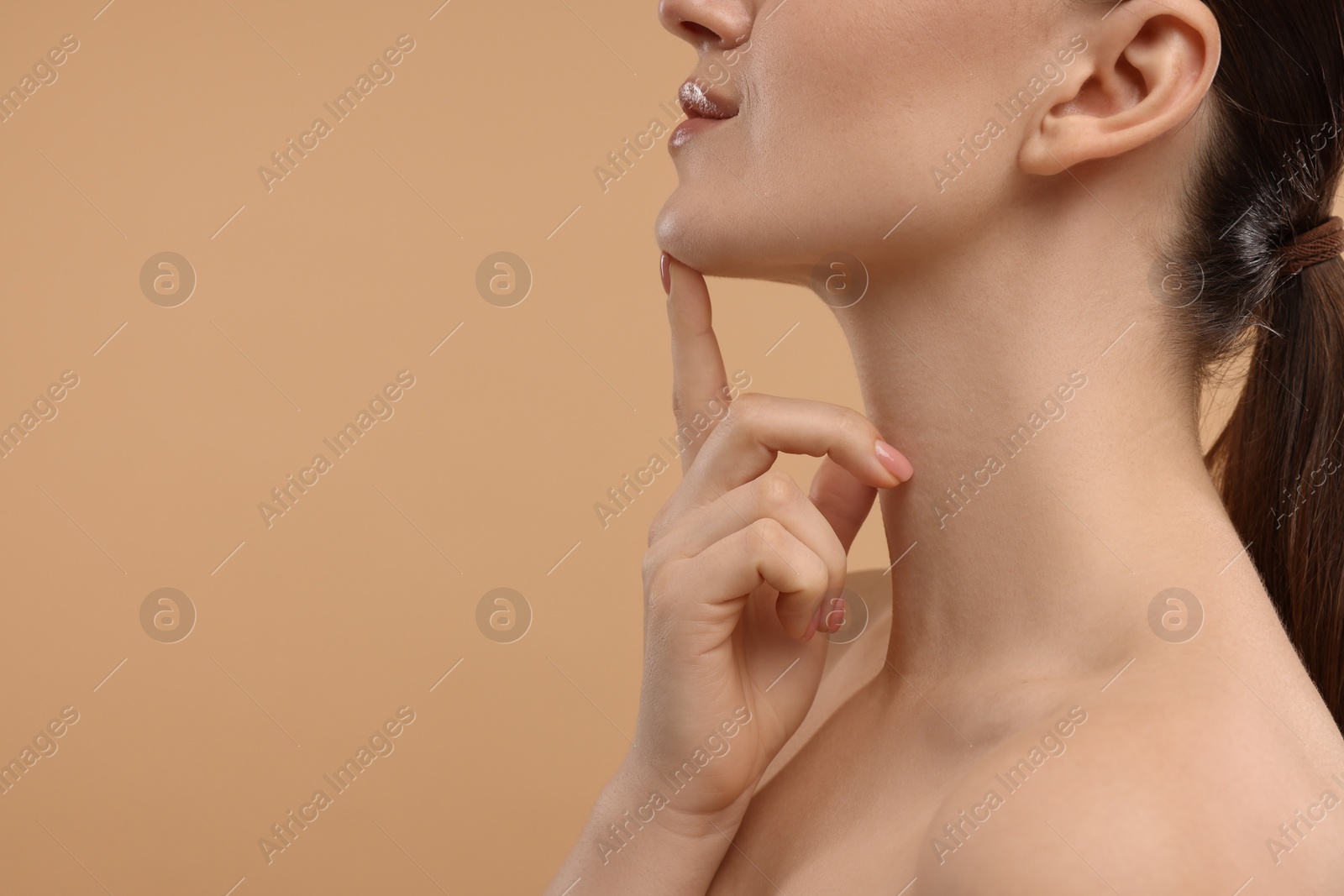 Photo of Woman touching her chin on beige background, closeup. Space for text