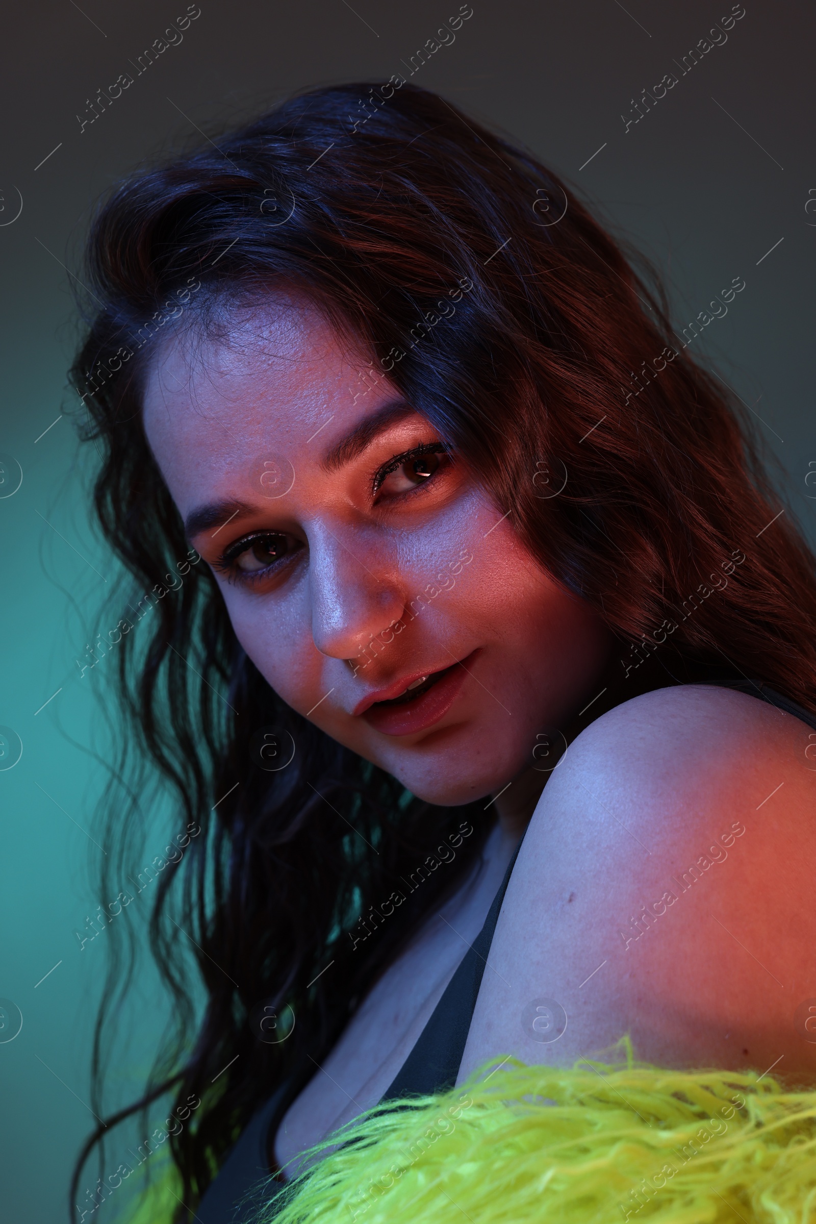 Photo of Portrait of beautiful woman in yellow fur coat on dark background with neon lights