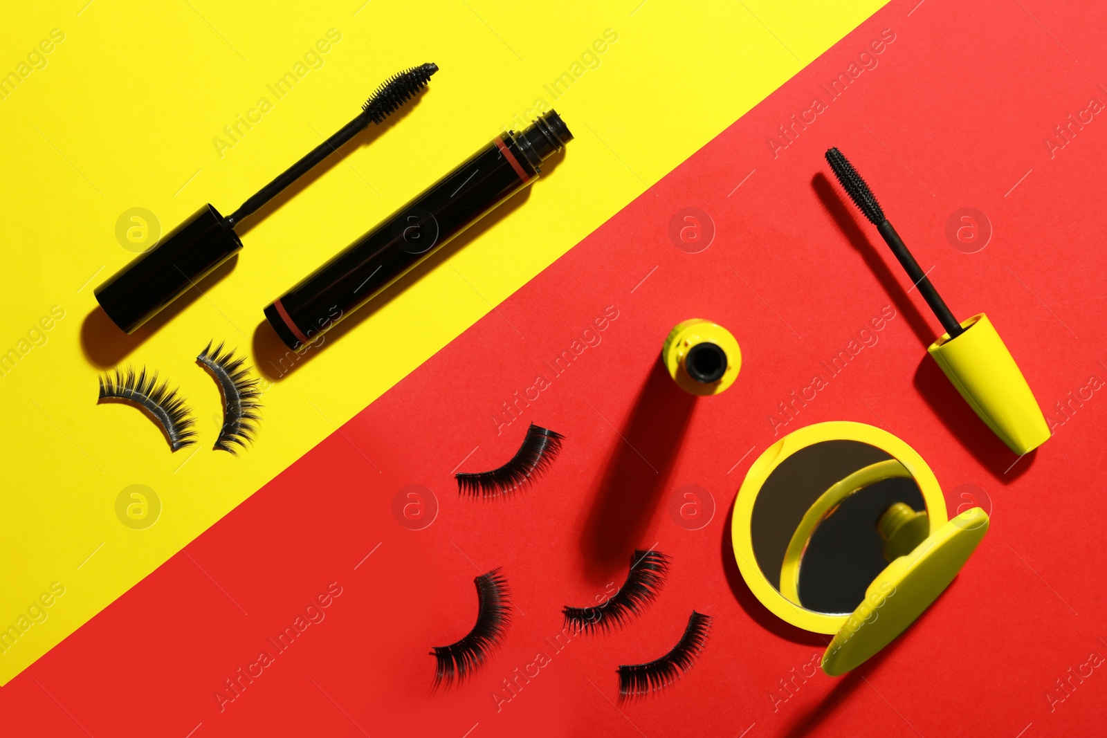 Photo of Different mascaras, fake eyelashes and mirror on color background, flat lay. Makeup product