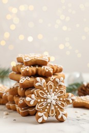 Photo of Tasty Christmas cookies on white marble table against blurred festive lights