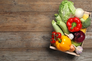 Photo of Fresh vegetables in crate on wooden background, top view. Space for text