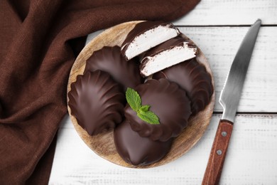 Photo of Delicious chocolate covered marshmallows with mint on white wooden table, flat lay