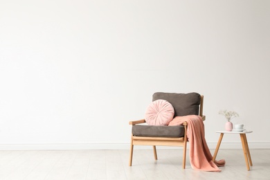 Photo of Stylish living room interior with comfortable armchair and wooden table near white wall. Space for text