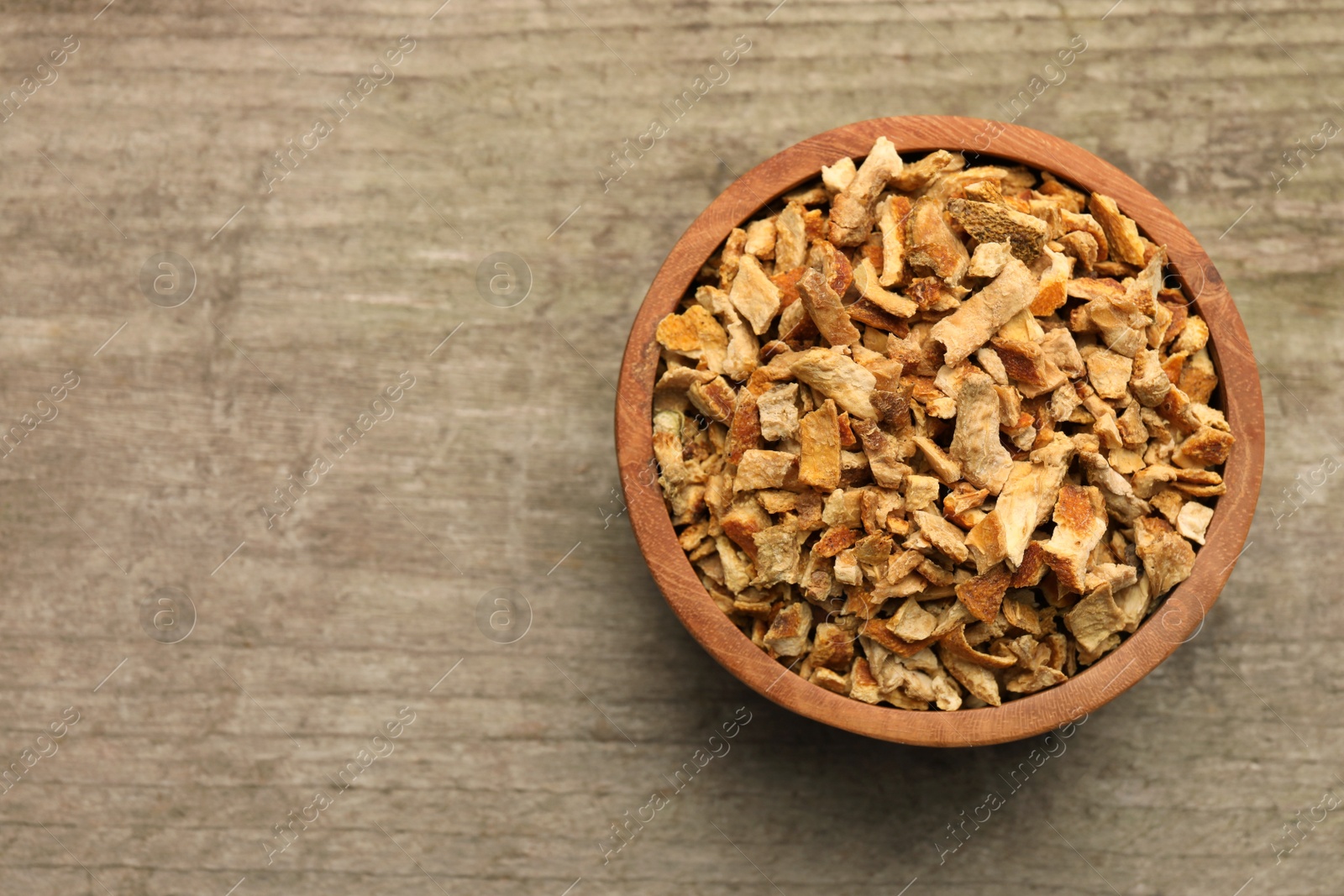 Photo of Bowl of dried orange zest seasoning on wooden table, top view. Space for text