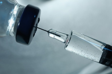 Filling syringe with COVID-19 vaccine on grey background, closeup