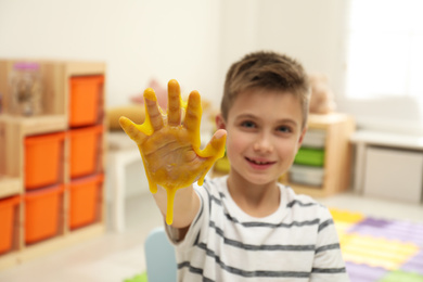 Photo of Little boy with slime in playroom, focus on hand