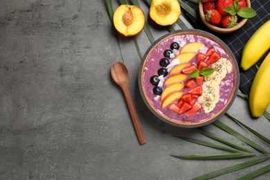 Photo of Delicious acai smoothie with fruits served on grey table, flat lay. Space for text
