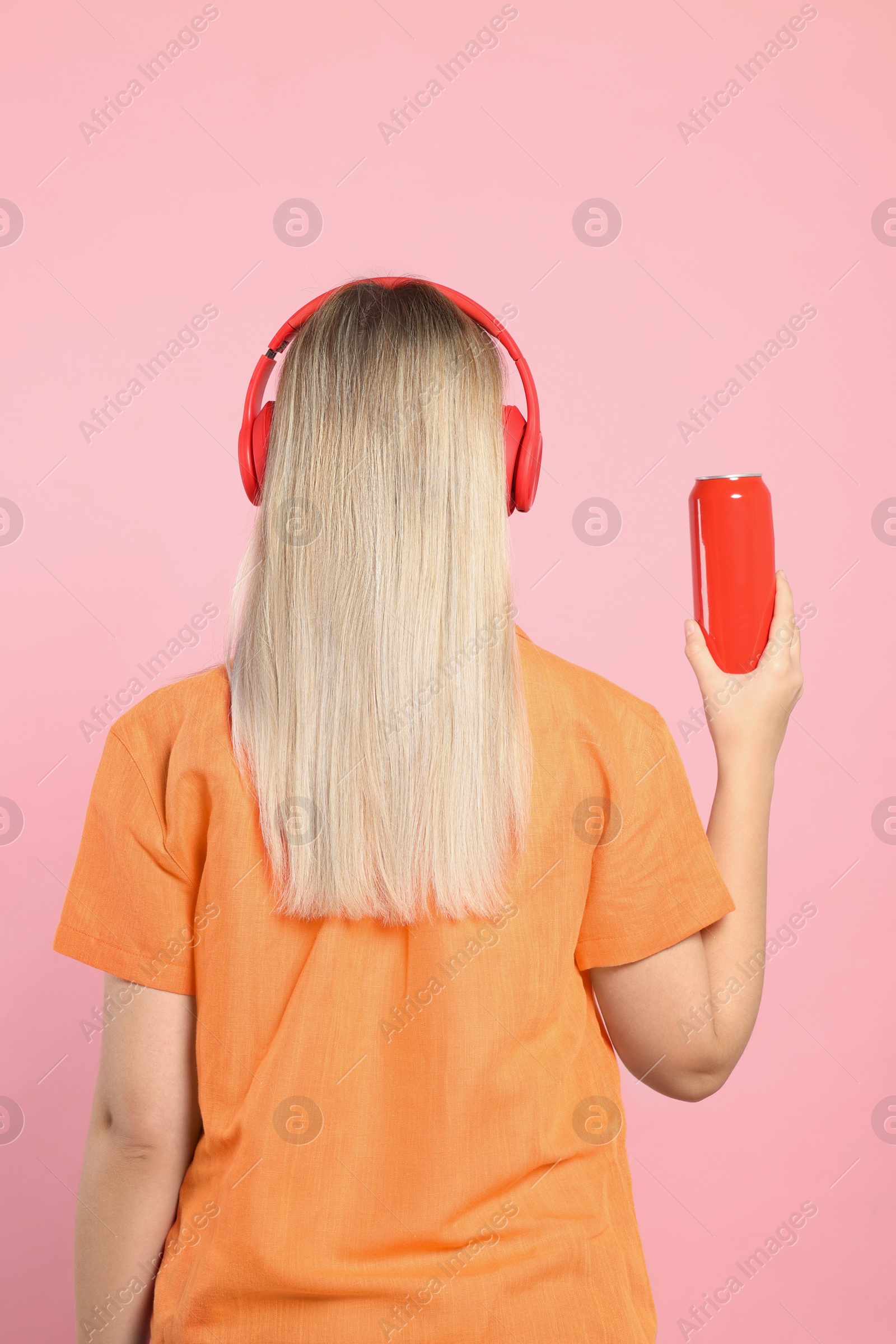 Photo of Woman holding red beverage can on pink background, back view