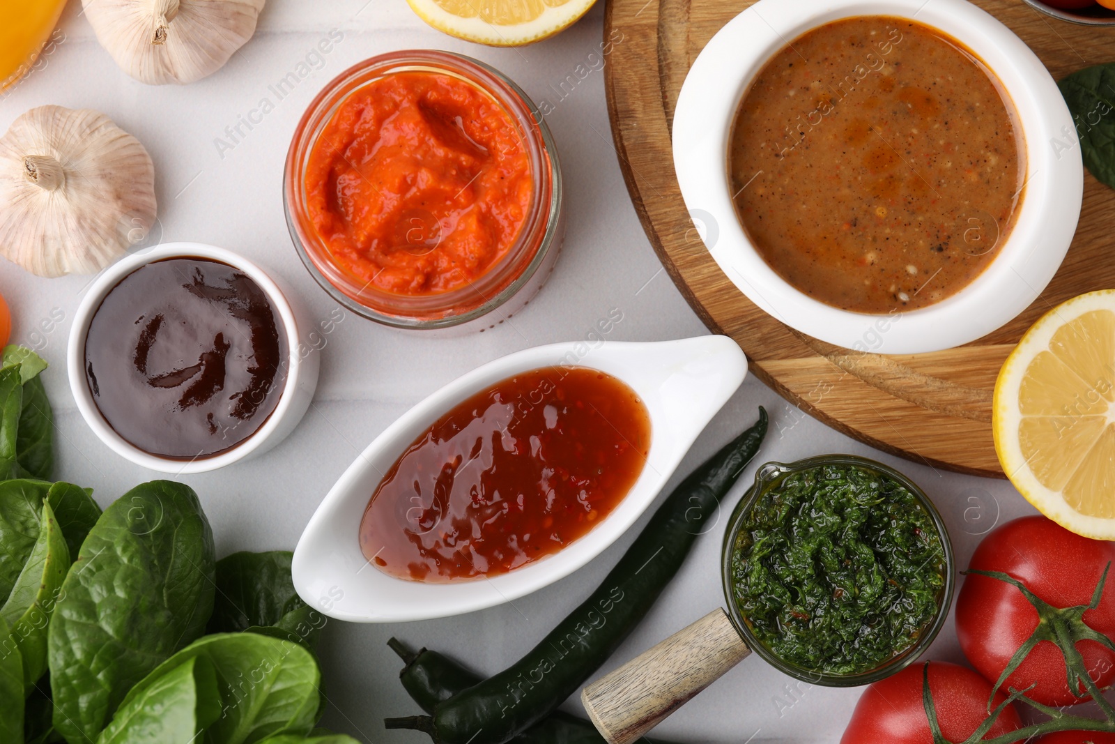 Photo of Different marinades and products on white tiled table, flat lay