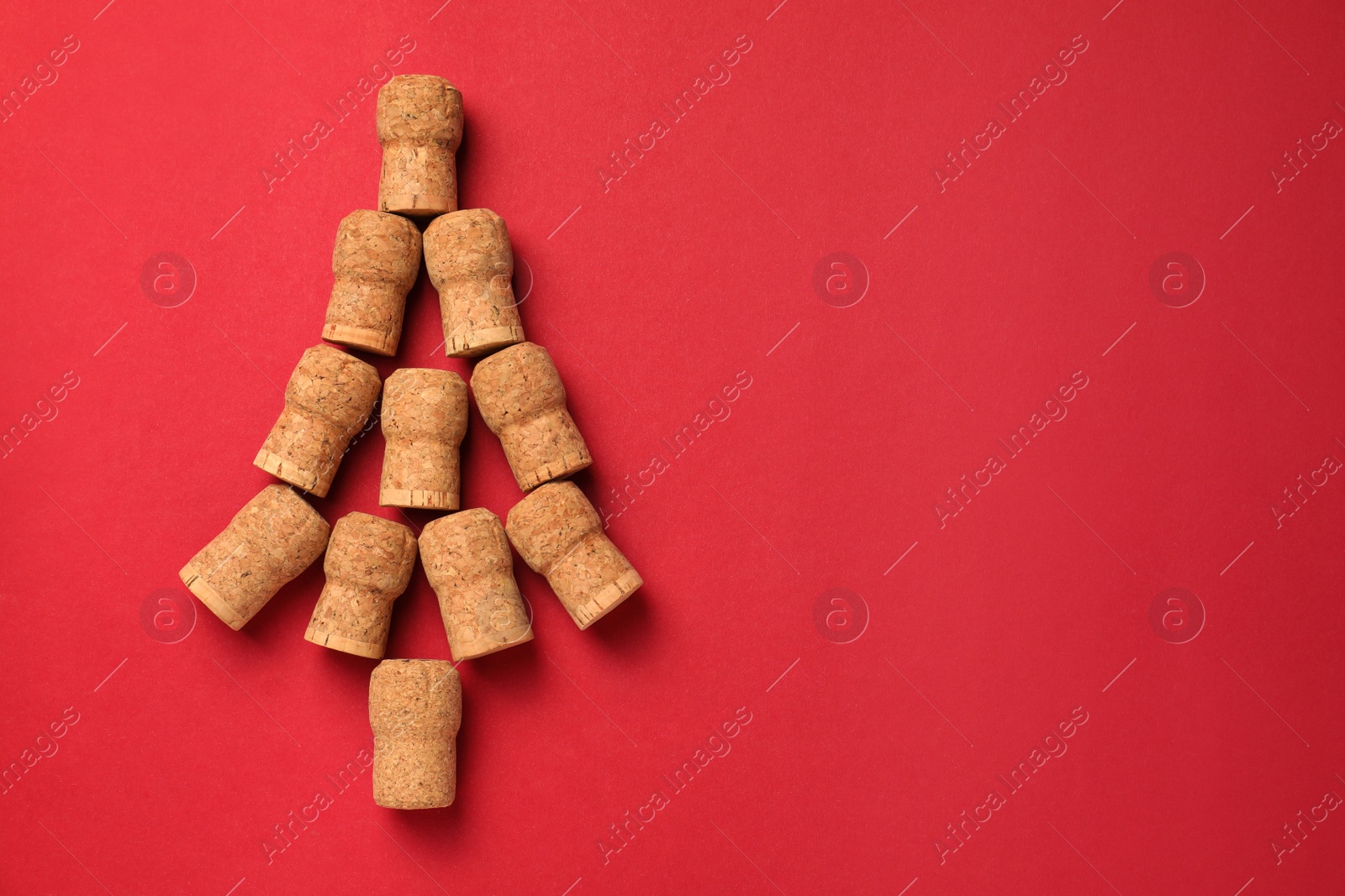 Photo of Christmas tree made of wine corks on red background, top view. Space for text