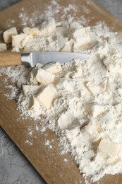 Photo of Making shortcrust pastry. Flour, butter, knife and wooden board on grey table