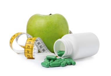 Photo of Weight loss pills, bottle, apple and measuring tape on white background