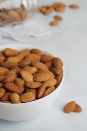 Photo of Bowl of delicious almonds on white marble table, closeup